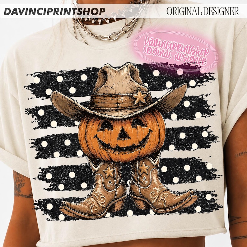 K&ouml;nnte beinhalten: Ein cremefarbenes T-Shirt mit einer Grafik eines orangefarbenen K&uuml;rbisses, der einen braunen Cowboyhut und braune Cowboystiefel tr&auml;gt. Das Design ist vor einem Hintergrund aus schwarzen horizontalen Streifen mit wei&szlig;en Punkten platziert.