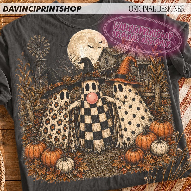 K&ouml;nnte beinhalten: Ein anthrazitfarbenes T-Shirt mit einer Grafik von drei Geistern mit Hexenh&uuml;ten auf einem Feld mit K&uuml;rbissen, einer Windm&uuml;hle und einem Haus unter einem Vollmond. Die Geister haben Blumen-, Karomuster und Punkte. Der Text lautet DAVINCIPRINTSHOP.