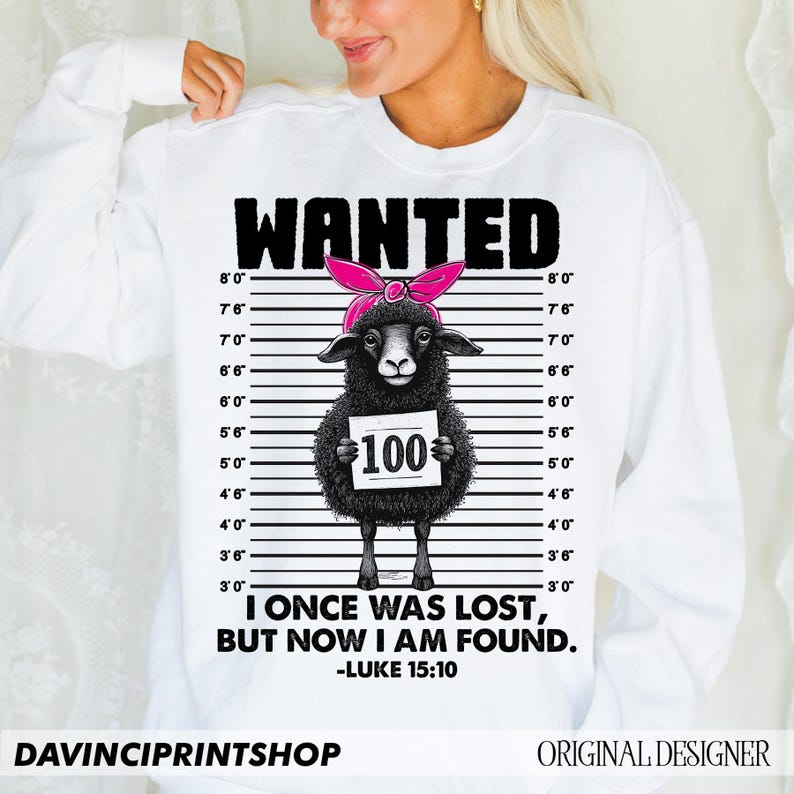 Puede incluir: Sudadera blanca con una ilustraci&oacute;n en blanco y negro de una oveja con un pa&ntilde;uelo rosa y sosteniendo un cartel que dice "100". El texto "WANTED" est&aacute; por encima de la oveja y el texto "I ONCE WAS LOST, BUT NOW I AM FOUND. -LUKE 15:10" est&aacute; por debajo de la oveja.