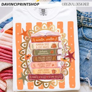 K&ouml;nnte beinhalten: Ein wei&szlig;es T-Shirt mit einer Grafik eines B&uuml;cherstapels und dem Text sweater weather, pumpkin spice & cozy nights, autumn adventures, falling leaves & books please, grateful heart happy soul, warm drinks good thinking, thankful blessed autumn obsessed.
