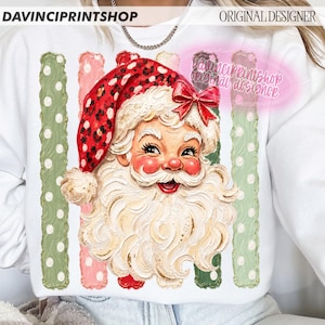 May include: A white sweatshirt featuring a graphic of Santa Claus with a red leopard print hat and a red bow. The design includes vertical stripes in alternating shades of sage green and light pink with white polka dots and textured brushstrokes.