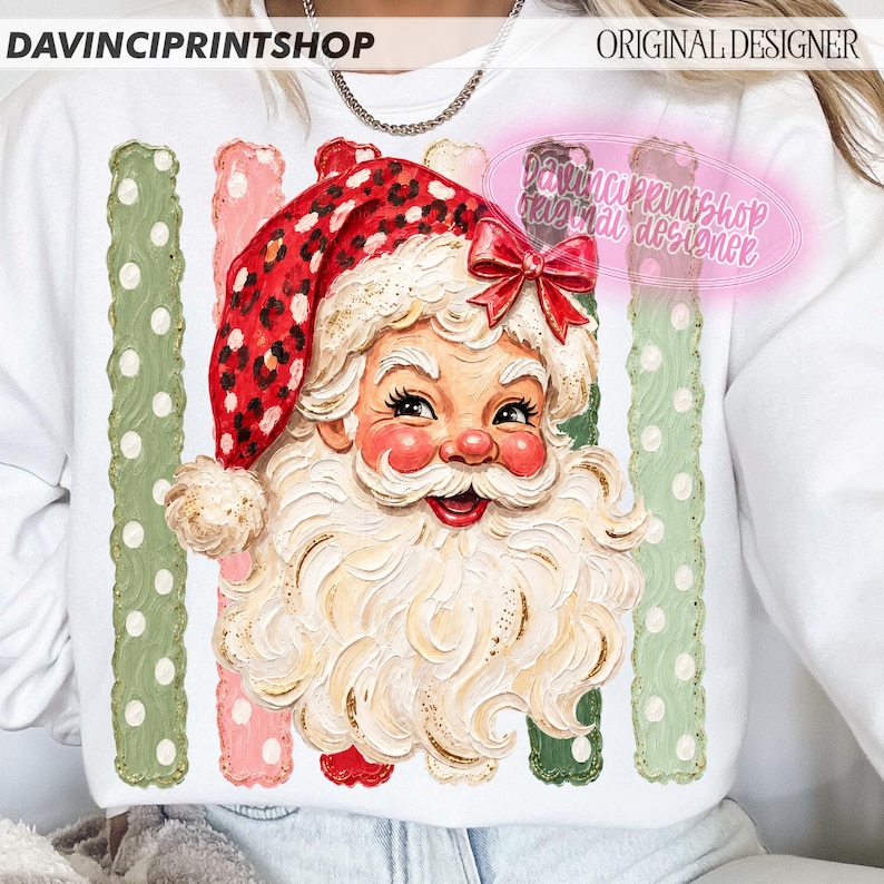 May include: A white sweatshirt featuring a graphic of Santa Claus with a red leopard print hat and a red bow. The design includes vertical stripes in alternating shades of sage green and light pink with white polka dots and textured brushstrokes.