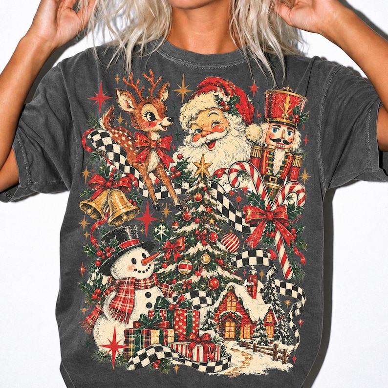 May include: A charcoal gray t-shirt featuring a vibrant Christmas-themed graphic print. The design includes a smiling Santa Claus, a reindeer, a nutcracker, a snowman, a decorated pine tree, wrapped gifts, and a black and white checkered ribbon.