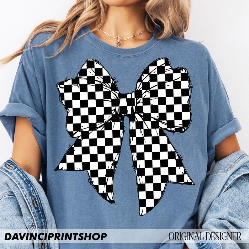 May include: A blue t-shirt featuring a large black and white checkered bow graphic. The shirt has short sleeves and a relaxed fit. The text "DAVINCIPRINTSHOP" is printed at the bottom left, and "ORIGINAL DESIGNER" is at the bottom right.