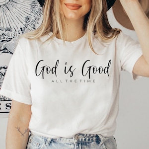 May include: White t-shirt with the text "God is Good All The Time" in black script.