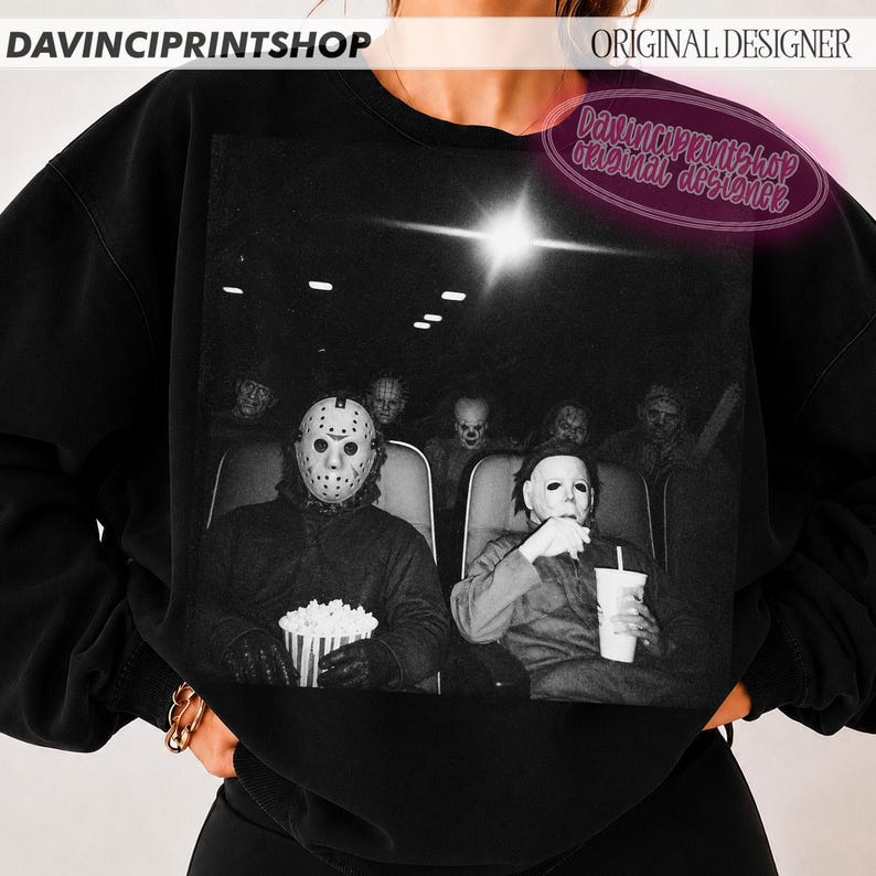 Peut inclure: Un sweat-shirt noir &agrave; col rond avec une grande impression graphique repr&eacute;sentant des personnages de films d'horreur assis dans un cin&eacute;ma. L'image montre des silhouettes masqu&eacute;es, dont Jason Voorhees et Michael Myers, tenant du pop-corn.