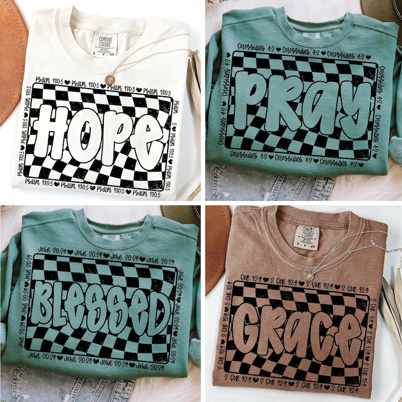 Op de afbeelding: Vier verschillende sweatshirts met een geruit patroon en een woord in een vetgedrukt, bubbelvormig lettertype. De woorden zijn "Hope", "Pray", "Blessed" en "Grace". Elk sweatshirt heeft een andere kleur en een ander bijbelvers dat rond het geruite patroon is gedrukt.
