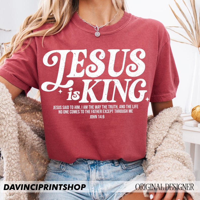 K&ouml;nnte beinhalten: Rotes T-Shirt mit wei&szlig;em Text, der "Jesus ist K&ouml;nig" lautet, und einem Bibelvers aus Johannes 14,6.