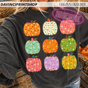 Puede incluir: Una sudadera de cuello redondo gris carb&oacute;n con un estampado gr&aacute;fico de nueve calabazas en varios colores, incluyendo naranja, blanco, rosa, turquesa, verde y morado. Cada calabaza est&aacute; decorada con un patr&oacute;n de peque&ntilde;os puntos multicolores.
