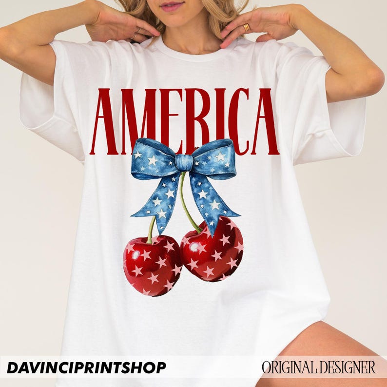 May include: White t-shirt with the word "AMERICA" printed in red letters. A blue bow with white stars is above the word, and two red cherries with white stars are below the bow.