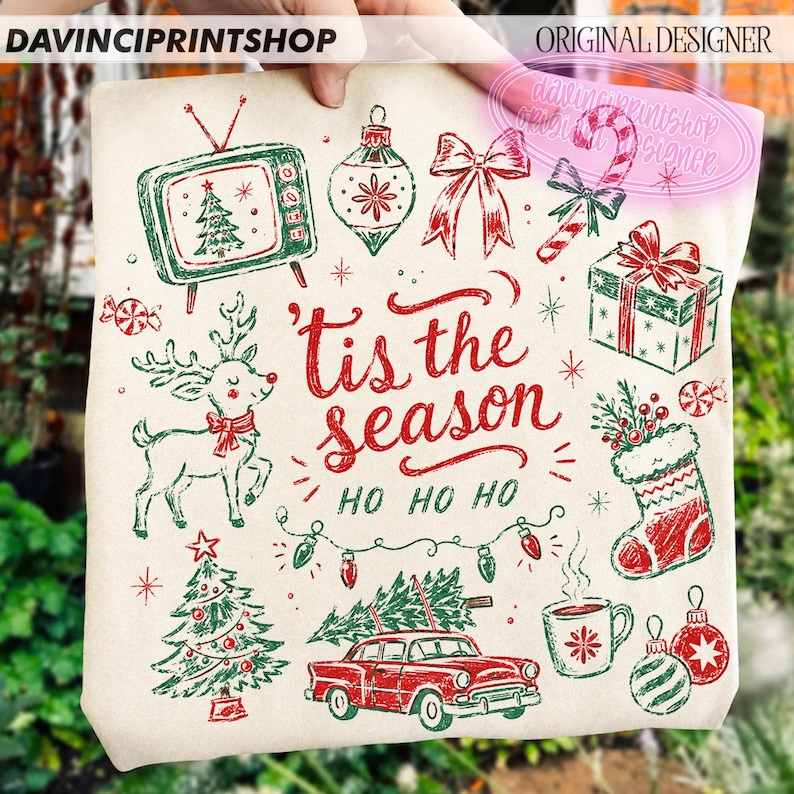 May include: A cream-colored tote bag featuring red and green Christmas illustrations including a vintage television, reindeer, car with a tree, gift, stocking, and ornaments. The text reads 'tis the season' and 'HO HO HO' in red script.