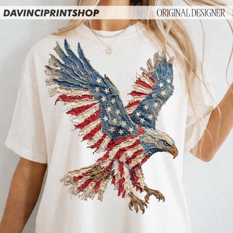 Pu&ograve; includere: T-shirt bianca con un design di aquila con bandiera americana invecchiata. Le ali dell'aquila sono in denim blu con stelle bianche e tessuto a righe rosse e bianche. Il testo "DAVINCIPRINTSHOP" e "ORIGINAL DESIGNER" sono in alto.