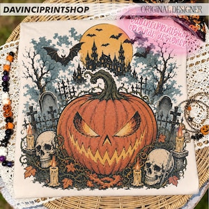 May include: A cream-coloured t-shirt featuring a graphic print of a large orange jack-o'-lantern with a jagged face, surrounded by two human skulls, lit candles, a dark castle silhouette, a full moon, bats, and a graveyard scene.