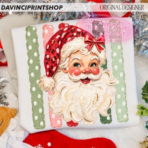 May include: A white sweatshirt featuring a graphic of Santa Claus with a red leopard print hat and a red bow. The design includes vertical stripes in sage green and light pink with white polka dots. The text DAVINCIPRINTSHOP and ORIGINAL DESIGNER appear.