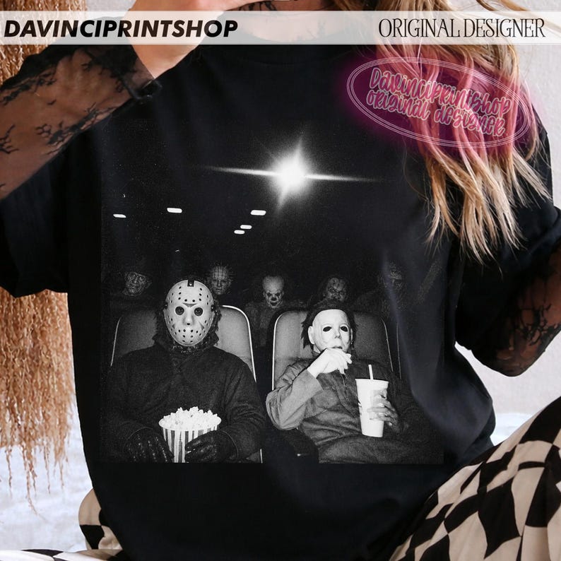 Peut inclure: Un t-shirt noir avec une impression graphique de personnages de films d'horreur assis dans une salle de cin&eacute;ma. Le motif montre des silhouettes portant des masques, dont un masque de hockey et un masque blanc, tenant du pop-corn. Texte DAVINCIPRINTSHOP.