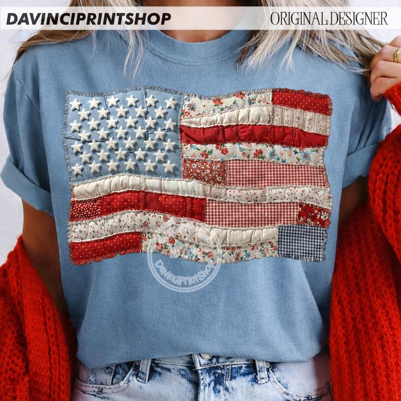 May include: A light blue t-shirt featuring a patchwork American flag design. The flag incorporates white stars on a blue field and red and white stripes with floral and gingham patterns. The text "DAVINCIPRINTSHOP" is visible at the top.
