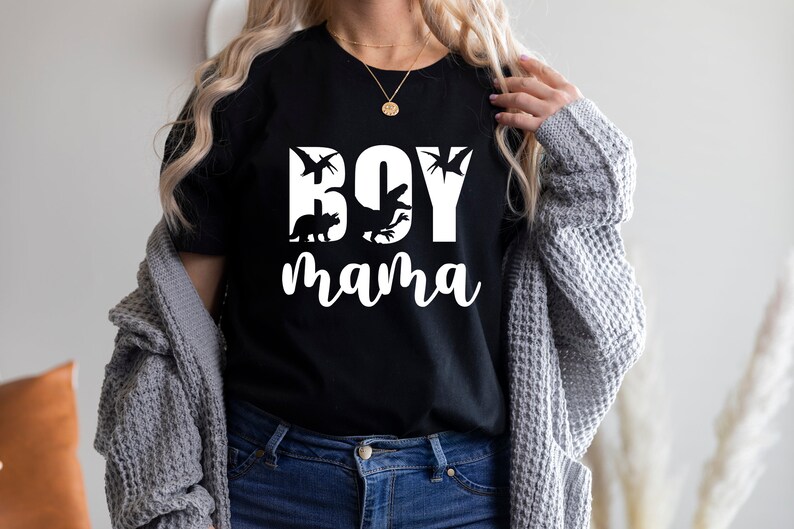 Pode incluir: Camiseta preta com texto branco que diz "Boy mama" com silhuetas de dinossauros.