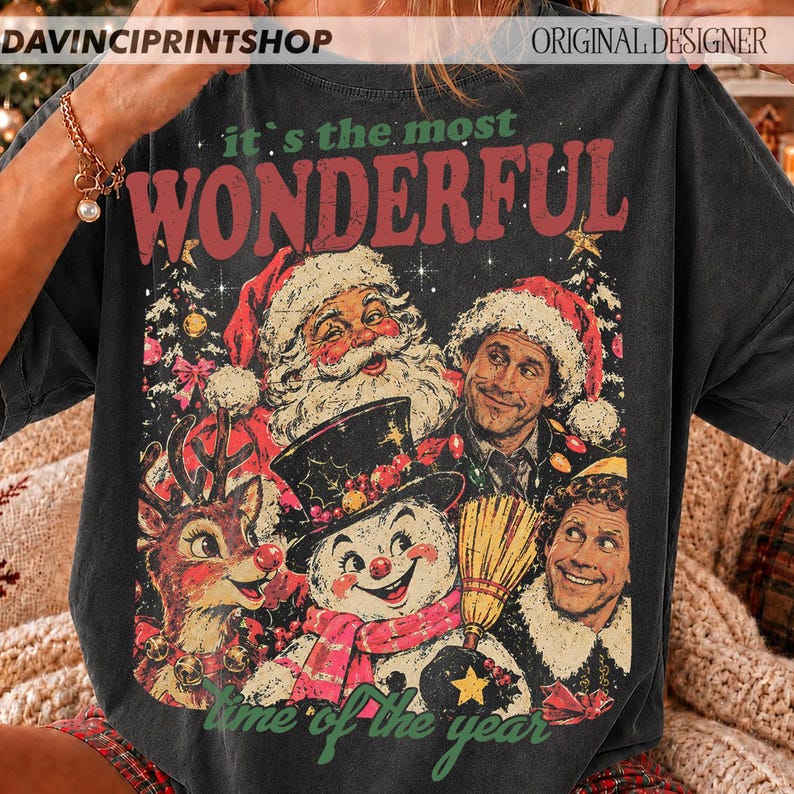 K&ouml;nnte beinhalten: Ein anthrazitfarbenes T-Shirt mit einem Grafikdruck und dem Text 'it's the most WONDERFUL time of the year'. Das Design zeigt Illustrationen vom Weihnachtsmann, einem Rentier, einem Schneemann und einem Mann mit Weihnachtsm&uuml;tze.