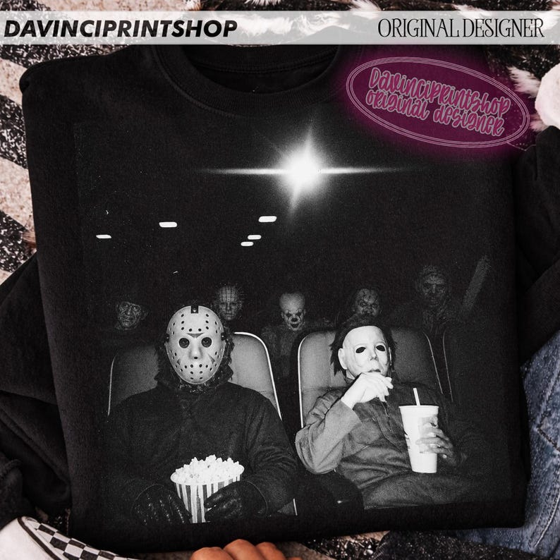 Peut inclure: Un sweat-shirt noir &agrave; col rond avec une impression graphique de personnages de films d'horreur assis dans une salle de cin&eacute;ma. L'image montre Jason Voorhees avec un seau de pop-corn et Michael Myers tenant une boisson, avec d'autres silhouettes.