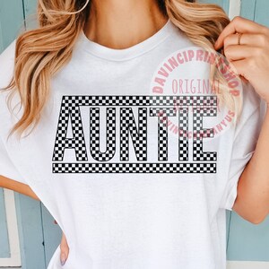 K&ouml;nnte beinhalten: Wei&szlig;es T-Shirt mit einem schwarz-wei&szlig;en Karomuster, auf dem in fetten Buchstaben "AUNTIE" steht.