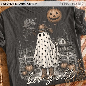 K&ouml;nnte beinhalten: Ein anthrazitfarbenes T-Shirt mit einer Grafik eines Geistes, der einen Cowboyhut und Stiefel tr&auml;gt und mit schwarzen Punkten bedeckt ist. Das Motiv zeigt einen K&uuml;rbis, ein Bauernhaus, eine Windm&uuml;hle und einen Vollmond. Der Text "boo y'all" ist wei&szlig; gedruckt.