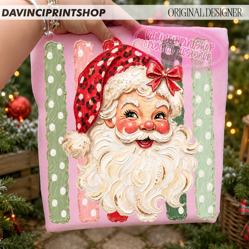 May include: A pink fabric panel featuring a central illustration of Santa Claus with a red leopard print hat and a red bow. The design includes vertical stripes in light green and pink with white polka dots and the text DAVINCPRINTSHOP.