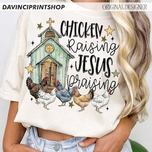 Peut inclure: T-shirt cr&egrave;me avec un motif fantaisiste. Le graphisme comprend une petite &eacute;glise, plusieurs poulets et les mots "Chicken Raising Jesus Praising" en &eacute;criture manuscrite. Le motif int&egrave;gre des &eacute;toiles et une croix.