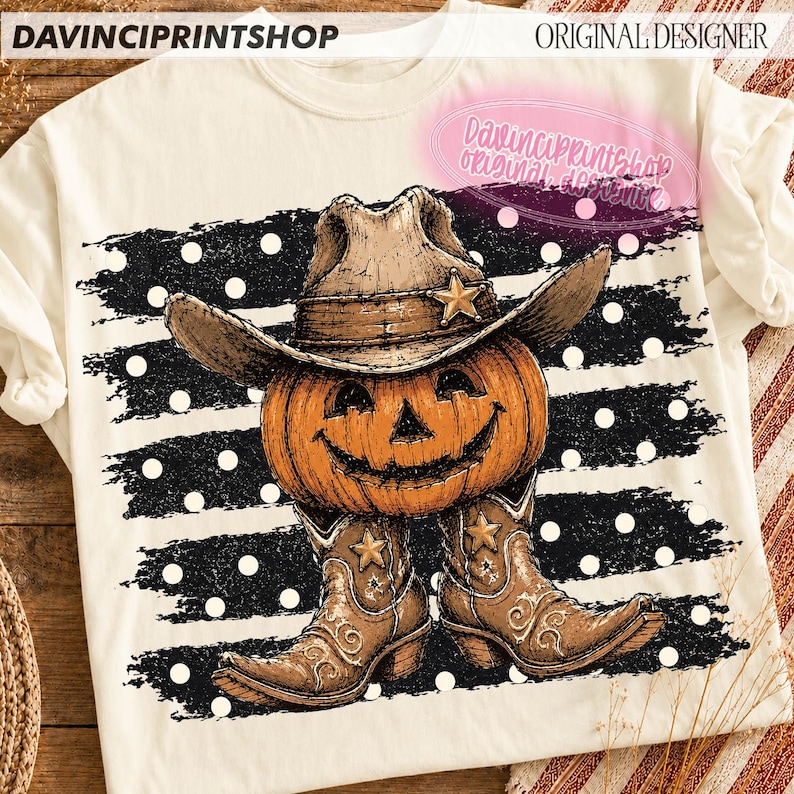 K&ouml;nnte beinhalten: Ein cremefarbenes T-Shirt mit einer Grafik eines K&uuml;rbisses, der einen braunen Cowboyhut und braune Cowboystiefel tr&auml;gt. Das Motiv ist vor einem Hintergrund aus schwarzen horizontalen Pinselstrichen mit wei&szlig;en Punkten und dem Text DAVINCIPRINTSHOP.