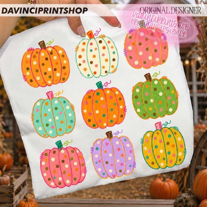 Puede incluir: Un art&iacute;culo de tela blanca con un patr&oacute;n repetitivo de nueve calabazas en varios colores, incluyendo naranja, verde azulado, rosa, verde, amarillo y morado. Cada calabaza est&aacute; decorada con lunares y tiene un tallo marr&oacute;n. El texto dice DAVINCPRINTSHOP.