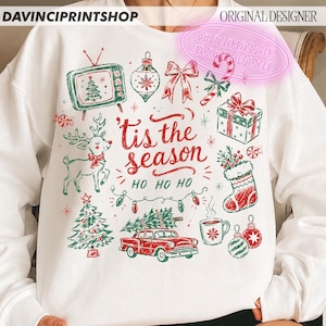 May include: A white crewneck sweatshirt featuring a red and green graphic print with the text 'tis the season HO HO HO'. The design includes a vintage television, reindeer, Christmas tree, car with a tree on top, gift, stocking, and ornaments.