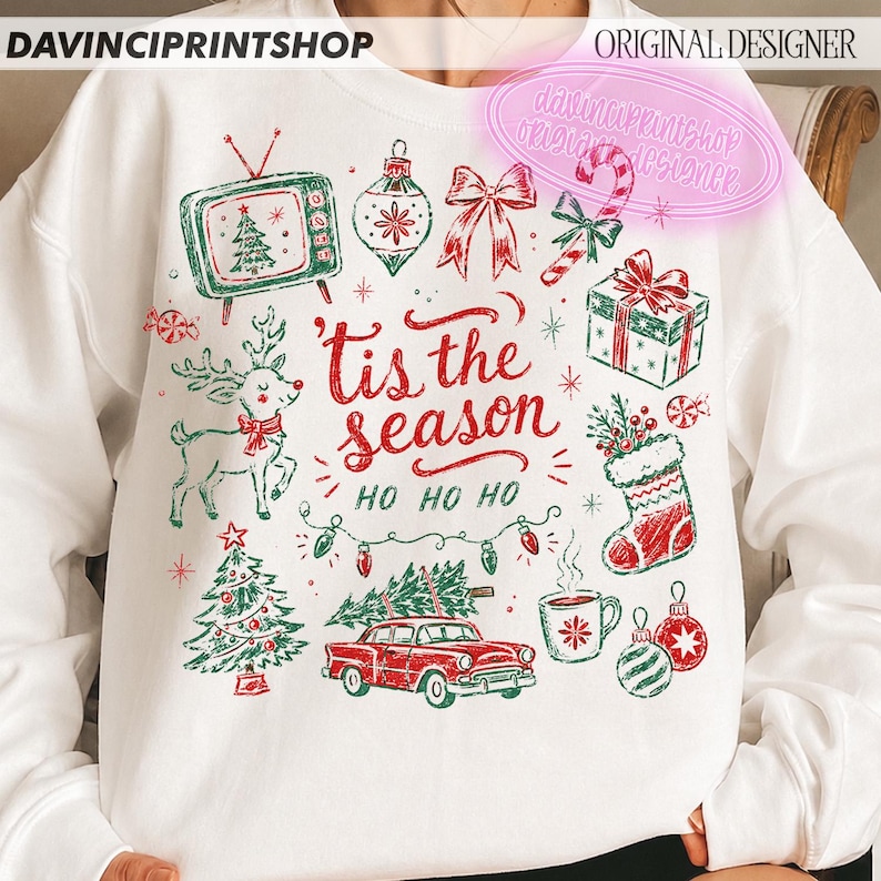May include: A white crewneck sweatshirt featuring a red and green graphic print with the text 'tis the season HO HO HO'. The design includes a vintage television, reindeer, Christmas tree, car with a tree on top, gift, stocking, and ornaments.
