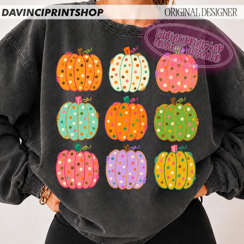 Puede incluir: Una sudadera de cuello redondo gris carb&oacute;n con un estampado gr&aacute;fico de nueve calabazas dispuestas en una cuadr&iacute;cula de tres por tres. Cada calabaza es de un color diferente, incluyendo naranja, blanco, rosa, turquesa y morado, con lunares.