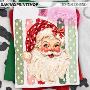 May include: A white t-shirt featuring a graphic of Santa Claus with a red leopard print hat and a red bow. The design includes vertical stripes in green and pink with white polka dots. The text DAVINCIPRINTSHOP and ORIGINAL DESIGNER appear.