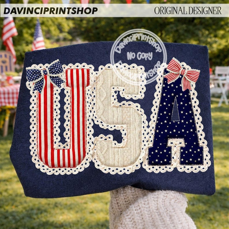 May include: Navy blue fabric with the letters "USA" appliqued in red and white stripes, cream cable knit, and navy blue with white stars. Each letter is outlined with white lace and topped with a bow. The text "DAVINCIPRINTSHOP" and "ORIGINAL DESIGNER" are visible.