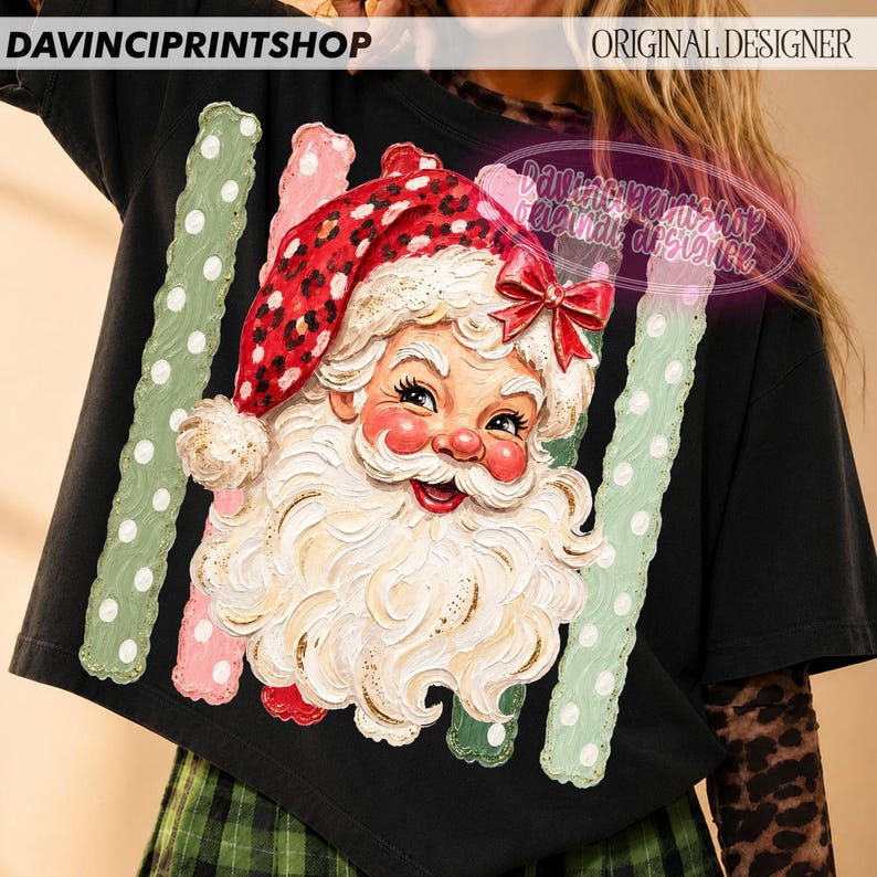 May include: A black t-shirt featuring a graphic of Santa Claus with a white beard and a red leopard print hat with a red bow. The design is flanked by two vertical light green scalloped stripes with white polka dots on a black background.