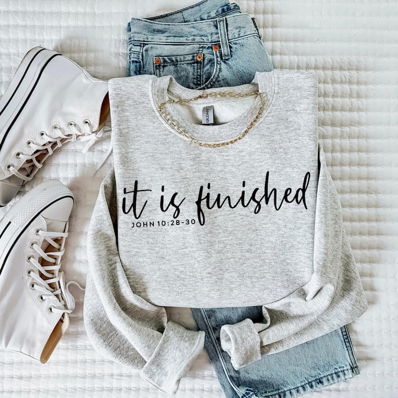 May include: Gray sweatshirt with the text "it is finished" and the scripture reference "JOHN 10:28-30" in black lettering.
