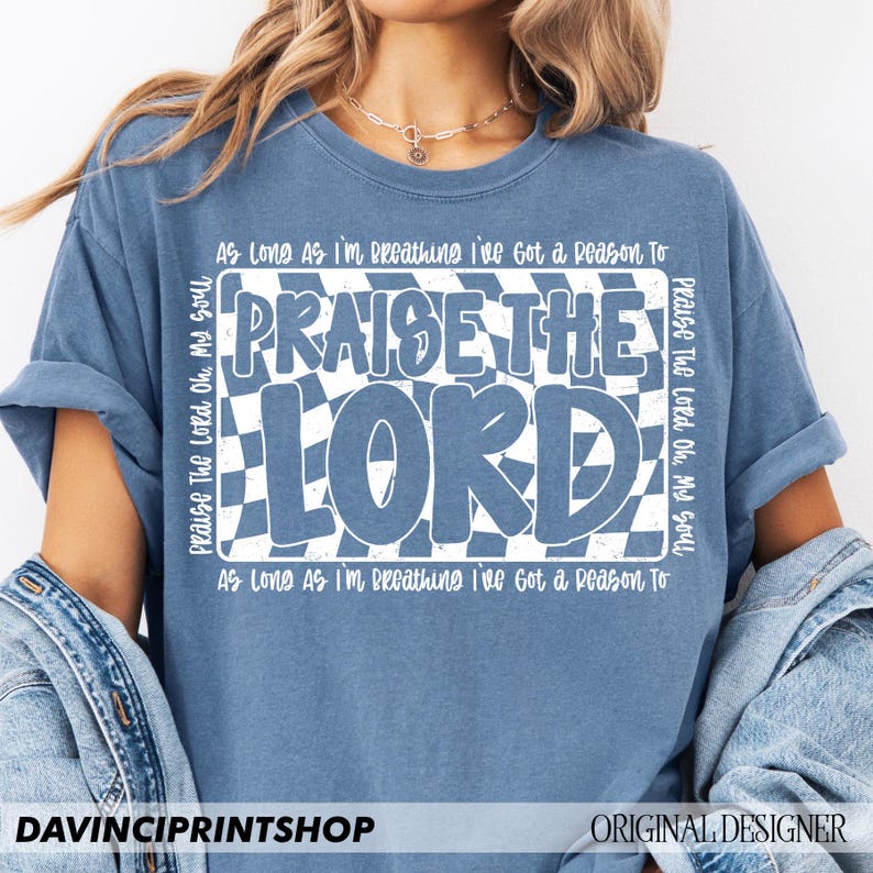 May include: A blue t-shirt with a white checkered design and the text "Praise The Lord" in white. The text "As Long As I'm Breathing I've Got a Reason To" is repeated at the top and bottom of the design.