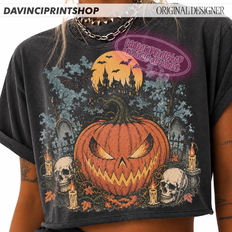 May include: A charcoal grey t-shirt featuring a graphic print of a large orange jack-o'-lantern with a menacing expression, surrounded by skulls, lit candles, a haunted castle silhouette, a full moon, and bats against a dark, spooky background.