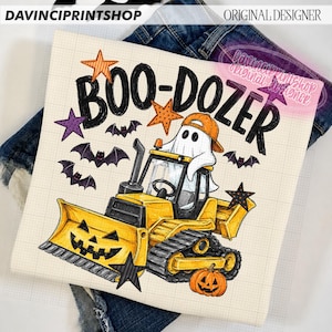 May include: A white t-shirt featuring a graphic of a yellow bulldozer with a jack-o'-lantern blade and a ghost wearing an orange baseball cap in the driver's seat. The text reads BOO-DOZER, surrounded by orange, purple, and black stars and bats.