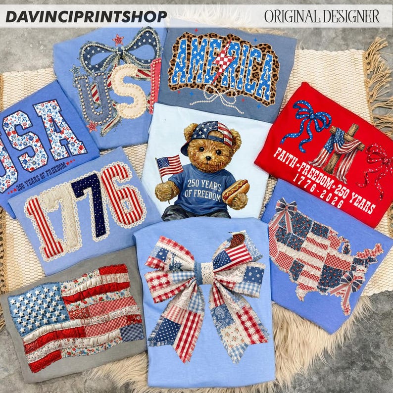 May include: Collection of patriotic t-shirts with various designs, including the American flag, the word "USA", and the number "1776". Some shirts feature a teddy bear holding a flag and a hot dog. The shirts are in shades of blue, red, and white.