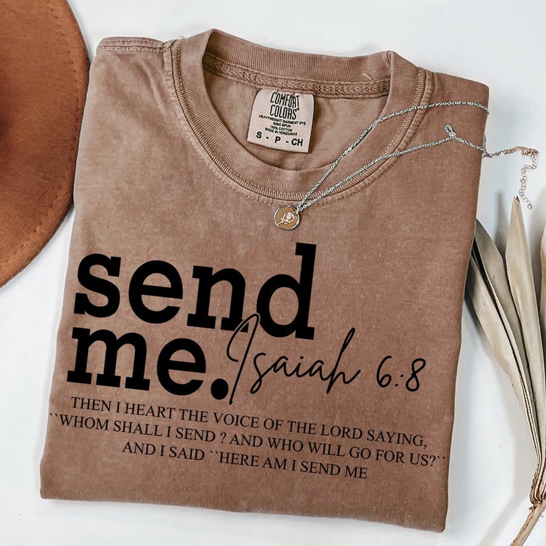 Pode incluir: Uma camiseta marrom com o texto "send me. Isaiah 6.8" e uma cita&ccedil;&atilde;o da B&iacute;blia: "Ent&atilde;o ouvi a voz do Senhor que dizia: Quem enviarei? E quem ir&aacute; por n&oacute;s?" E eu disse: "Eis-me aqui, envia-me."