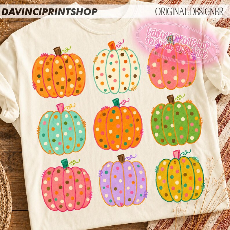 Puede incluir: Una camiseta de color crema con un estampado gr&aacute;fico de nueve calabazas de varios colores, incluyendo naranja, blanco, rosa, verde azulado, verde y morado. Cada calabaza est&aacute; decorada con lunares coloridos y tiene un peque&ntilde;o tallo verde.