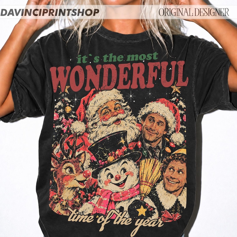 K&ouml;nnte beinhalten: Ein schwarzes Kurzarm-T-Shirt mit einem Grafikdruck und dem Text "it's the most WONDERFUL time of the year". Das Design zeigt Illustrationen vom Weihnachtsmann, einem Schneemann, einem Rentier und zwei M&auml;nnern in festlicher Kleidung.