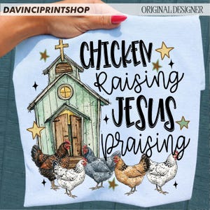 Peut inclure: T-shirt bleu clair avec une illustration d'&eacute;glise et le texte "CHICKEN Raising JESUS Praising". Le motif comprend des illustrations de poulets. Le t-shirt est tenu par une personne.