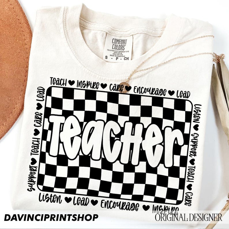 May include: A white t-shirt with a black and white checkered design and the word "Teacher" in a bold, white font. The words "Support, Teach, Care, Lead, Listen, Lead, Encourage, Inspire" are printed around the checkered design.