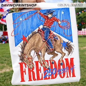 May include: White tote bag featuring a cowboy riding a horse, with the word "FREEDOM" in red. The design includes a blue background with stars and the text "250 years of". The top left corner has the text "DAVINCIPRINTSHOP" and the top right corner has the text "ORIGINAL DESIGNER".