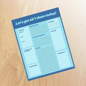 以下が含まれることがあります： 「Let's get sh*t done today!」というテキストが上部に書かれた、青と水色の印刷可能なデイリープランナー。プランナーには、優先事項、食事、予定、人生の指針、やるべきこと、水、メモ、ワークアウトのセクションが含まれています。