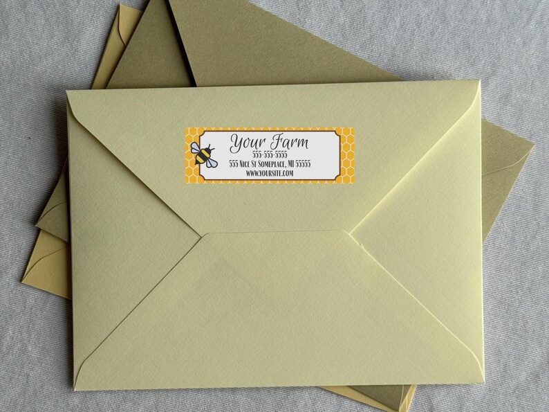 May include: A light yellow envelope with a bee-themed label. The label features a cartoon bee, honeycomb pattern, and the text "Your Farm" along with address and website information. Additional envelopes are visible.