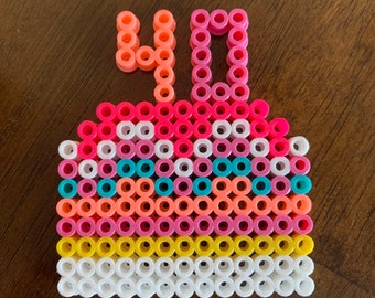 May include: A colorful, pixelated design of a cake with the number 40 on top. The cake features layers of white, yellow, pink, orange, and teal beads. The number 40 is in orange and pink beads. This handmade item is perfect for a birthday.