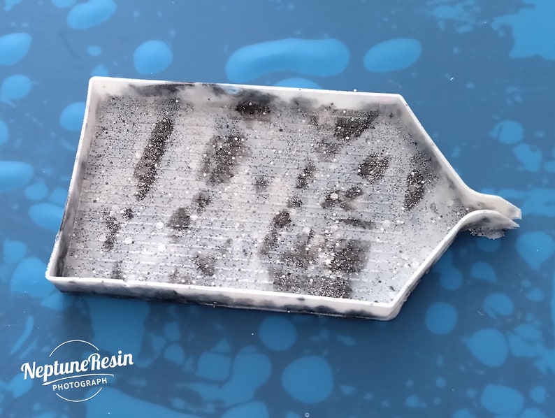 May include: A white plastic diamond painting tray with a textured surface and a small spout on the side. The tray is filled with black diamond painting drills.